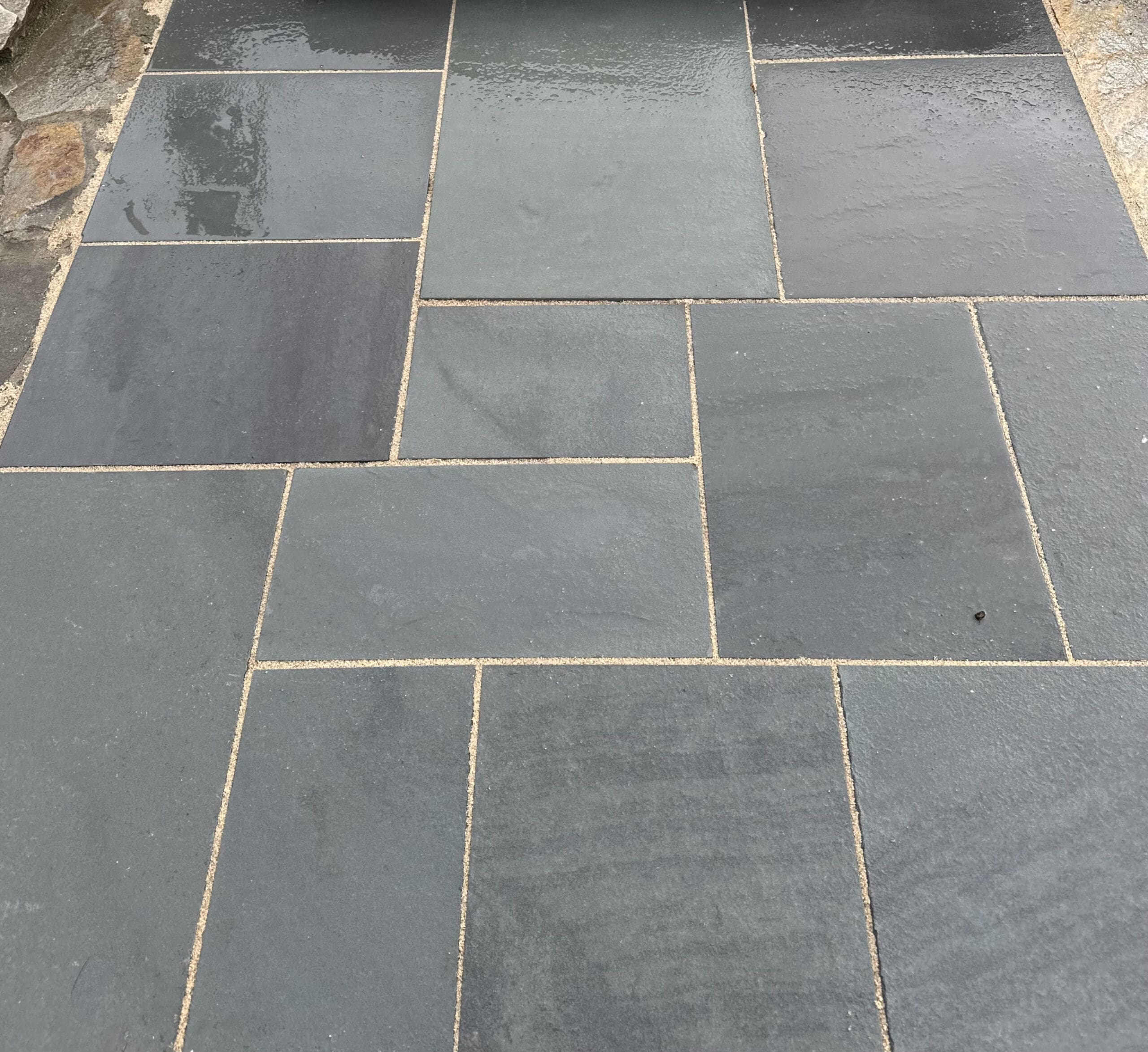 A bluestone walkway, that looks like it was recently wetted, showcasing its durability in the weather.
